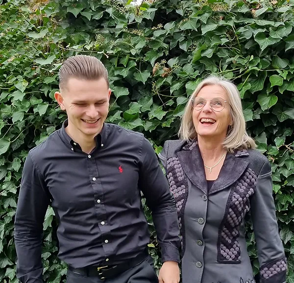 Dylan en Monique lachend voor een groene haag